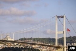 Atlet Estonia Jaan Roose berjalan di atas tali di atas Jembatan Martir (Bosphorus) di Istanbul, 15 September 2024. (KEMAL ASLAN / AFP)