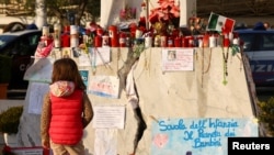 A child stands in front of candles, cards and other tributes to Pope Francis, outside Gemelli Hospital where the pope is being treated, in Rome, Italy, March 6, 2025.