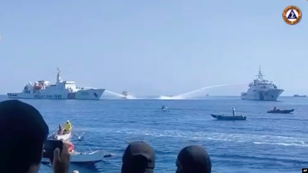 FILE - In this image taken from video provided by the Philippine coast guard, two Chinese ships aim their water cannons on a Philippine Bureau of Fisheries and Aquatic Resources vessel, center, as it approaches Scarborough Shoal in the disputed South China Sea on Dec. 9, 2023. 