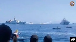 FILE - In this image taken from video provided by the Philippine coast guard, two Chinese ships aim their water cannons on a Philippine Bureau of Fisheries and Aquatic Resources vessel, center, as it approaches Scarborough Shoal in the disputed South China Sea on Dec. 9, 2023. 