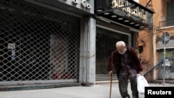 FILE - A homeless man walks past closed shops during a countrywide lockdown to combat the spread of the coronavirus disease in Beirut, Lebanon, April 3, 2020.