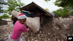 Residents salvage a mattress from a home partly submerged in mud from a mudslide triggered by Tropical Storm Erika in Montrouis, Haiti, Aug. 29, 2015.