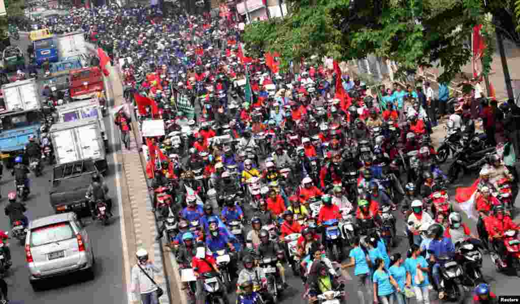 Para pekerja mengendarai motor sepanjang jalan selama demonstrasi di daerah industri di Tangerang. 