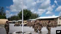 En esta foto del 26 de agosto de 2019, publicada por la Fuerza Aérea de EE.UU., aviadores del 475 ° Escuadrón de la Base Aérea Expedicionaria realizan una ceremonia de izado de banderas, en Camp Simba, Manda Bay, Kenia.