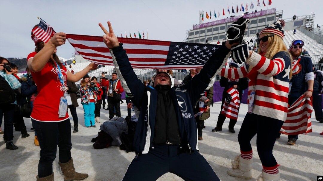 FILE - Fans celebrate with a U.S. flag after Jamie Anderson of the United States won the women's snowboard slopestyle final at the 2014 Winter Olympics, Feb. 9, 2014