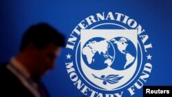 FILE - A participant stands near a logo of IMF at the International Monetary Fund - World Bank Annual Meeting 2018 in Nusa Dua, Bali, Indonesia, Oct. 12, 2018. 