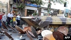 FILE- Iranian soldiers destroying satellite dishes with an army tank in the southwestern city of Shiraz. Iranian authorities carry out regular crackdowns to remove satellites from rooftops, and issue warnings against their use, Sept. 28, 2013.