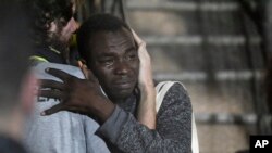 Sur cette photo prise le mardi 20 août 2019, un homme pleure alors qu'il étreint un membre d'équipage après avoir débarqué du navire de sauvetage Open Arms sur l'île sicilienne de Lampedusa, dans le sud de l'Italie. 