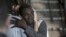 Sur cette photo prise le mardi 20 août 2019, un homme pleure alors qu'il étreint un membre d'équipage après avoir débarqué du navire de sauvetage Open Arms sur l'île sicilienne de Lampedusa, dans le sud de l'Italie. 