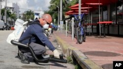 Petugas menyemprot bahan kimia ke dalam saluran pembuangan di Pantai Miami, Florida, dalam upaya melawan virus Zika (23/8). (AP/Alan Diaz)