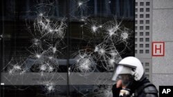 A police officer walks by a damaged building in the European Union quarter during a demonstration against COVID-19 measures in Brussels, Belgium.