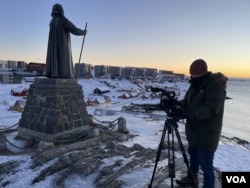 VOA's reporter Henry Ridgwell films next to the statue of Hans Egede, the Christian missionary who brought Danish rule to Greenland, Jan. 14, 2025. (Photo by Mikkel Noa Klein)