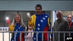 El presidente venezolano Nicolás Maduro enciende la luz de su teléfono, al igual de su esposa, Cilia Flores, al votar en Caracas, este 28 de julio de 2024.