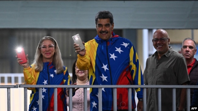 El presidente venezolano Nicolás Maduro enciende la luz de su teléfono, al igual de su esposa, Cilia Flores, al votar en Caracas, este 28 de julio de 2024.