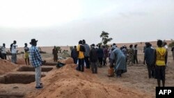 FILE - Officials and residents stand near freshly dug graves on June 11, 2019, in the Dogon village of Sobane-Kou, Mali, after an attack that killed dozens of ethnic Dogon on June 9, 2019. The mayor of a neighboring town blamed a Fulani militia group.