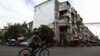 A cyclist rides pass the northern wall of Phnom Penh’s White Building where a painted mural of a woman’s portrait was white-washed controversially by the Phnom Penh Municipality. (Aun Chhengpor/VOA Khmer)