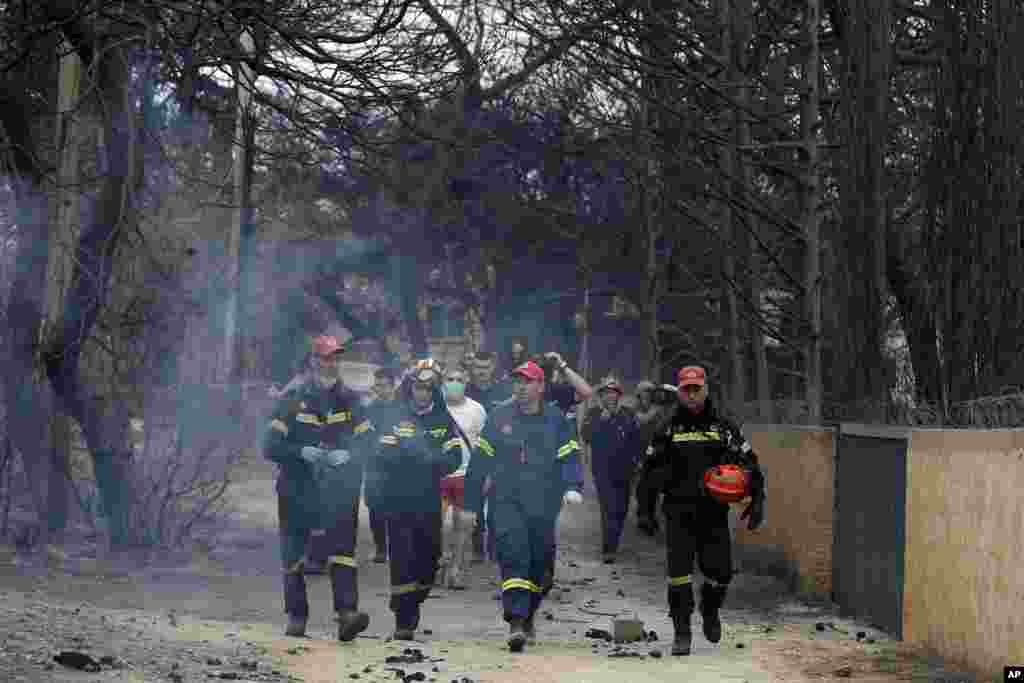 Firefighters inspect a burned area in Mati, east of Athens, Tuesday, July 24, 2018.