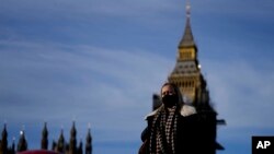 Seorang perempuan menggunakan masker ketika ia berjalan melalui jembatan Westminster di, London, pada 9 Desember 2021. (Foto: AP/Frank Augstein)