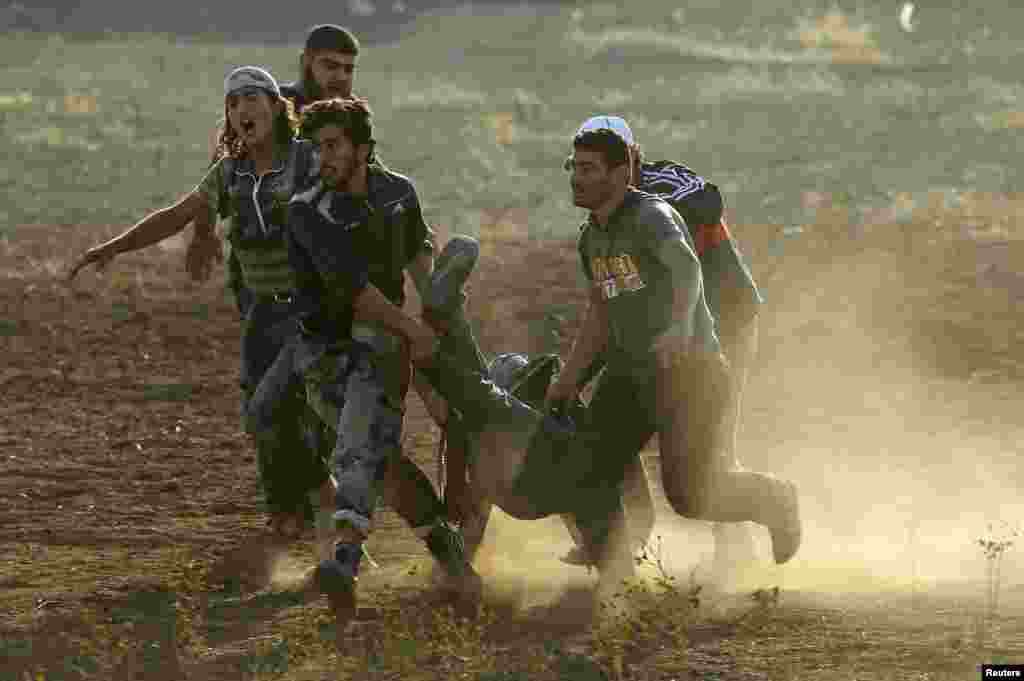 Free Syrian Army (FSA) fighters help a fellow fighter who was wounded during what the FSA said was an airstrike by forces loyal to Syria's President Bashar al-Assad in the southern Idlib countryside July 9, 2014.