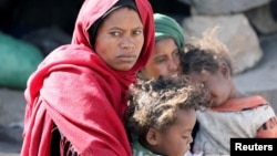 A woman looks as she sits with her children at a camp for internally displaced people on the outskirts of Sanaa, Yemen, March 1, 2021. 