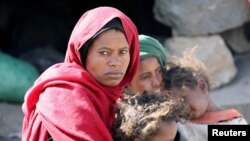 A woman looks as she sits with her children at a camp for internally displaced people on the outskirts of Sanaa, Yemen, March 1, 2021. 