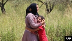 A Syrian refugee living with others in makeshift tents in south Lebanon hugs her child after an Israeli air strike targeted the outskirts of Burj al-Muluk on July 20, 2024.