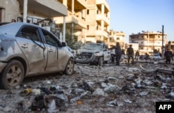 People check damage in a street following an airstrike by Syrian government forces in the town Maarrat Misrin, in Syria’s northwestern Idlib province, Feb. 25, 2020.