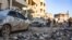 People check damage in a street following an airstrike by Syrian government forces in the town Maarrat Misrin, in Syria’s northwestern Idlib province, Feb. 25, 2020. 