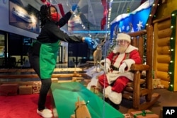 LaToya Booker cleans a transparent barrier between visitors for Santa at a Bass Pro Shop in Bridgeport, Conn., Nov. 10, 2020.