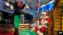 LaToya Booker cleans a transparent barrier between visitors for Santa at a Bass Pro Shop in Bridgeport, Conn., Nov. 10, 2020. 