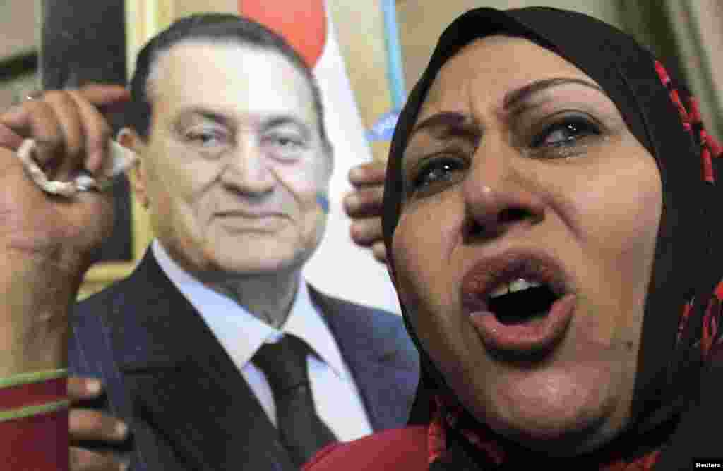 A supporter of ousted former Egyptian President Mohammed Hosni Mubarak stands near a poster of him at a protest outside a High Court in Cairo, December 23. 