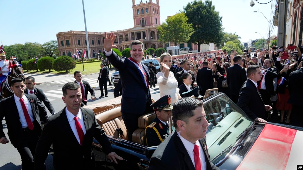 El nuevo presidente de Paraguay, Santiago Peña, y su esposa, Leticia Ocampos, saludan desde un automóvil mientras se dirigen a la Catedral el día de la asunción de Peña en Asunción, Paraguay, el martes 15 de agosto de 2023. 