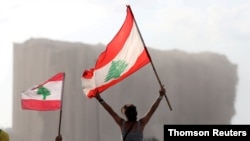 Demonstrators wave Lebanese flags during protests near the site of a blast at Beirut's port area, August 11, 2020.