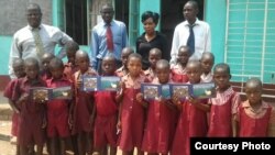 FILE: Children with some teachers at Musengezi Primary School displaying some of the books sourced from overseas donors.