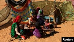 FILE - People rest next to shelters at the Zamzam camp for internally displaced persons near El Fasher in North Darfur, Feb. 4, 2015.