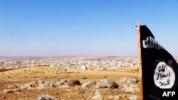 FILE - The trademark Islamic State flag is seen in the Mishtenur area, a plateau south of Kobani, Syria, Oct. 10, 2014. With IS militants losing their grip over their traditional Syrian strongholds, some say the militants may be left next year with control just of the eastern Syrian province of Deir Ezzor. 