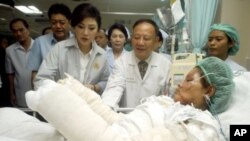 Thailand's Prime Minister Yingluck Shinawatra, third left, visits a victim of Saturday's car bomb attacks at a hospital in Hat Yai Songkhla province, southern Thailand, April 2, 2012. 