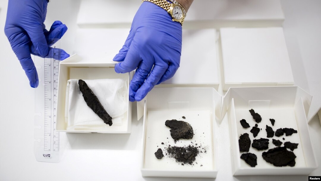 Seorang teknisi di Israel Antiquities Authority menunjukkan gulungan (kiri), yang ditemukan tahun 1970 tapi baru dianalisis, di Museum Israel di Yerusalem (20/7).