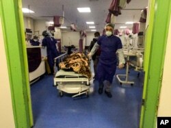 FILE - A medic moves a patient in a ward dedicated for people infected with the coronavirus at Forqani Hospital, in Qom, 125 kilometers south of Tehran, Iran, Feb. 26, 2020.
