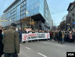 Građani nose transparent u znak podrške studentima tokom protesnog skupa na prilazu Trgu Slavija, u Beogradu, 22. decembra 2024. (Foto: Glas Amerike)