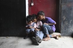 FILE - Children play on a cell phone at a market in New Delhi, India.