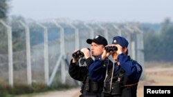 Hungarian and Polish policeman patrol at the Hungary and Serbia border fence near the village of Asotthalom, Hungary, Oct. 2, 2016 as Hungarians vote in a referendum on the European Union's migrant quotas. 