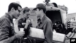 In this undated photo taken some time in the early to mid 1960s, from L to R, reporters David Halberstam (New York Times), Malcolm Brown (Associated Press) and Neil Sheehan (UPI) chat beside a helicopter in Vietnam.