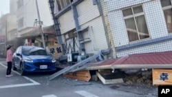 一名女子站在台灣花蓮被地震震得歪斜的建築旁。 （2024年4月3日）