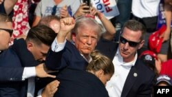 TOPSHOT - Republican candidate Donald Trump is seen with blood on his face surrounded by secret service agents as he is taken off the stage at a campaign event at Butler Farm Show Inc. in Butler, Pennsylvania, July 13, 2024.