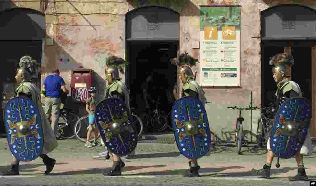 Men dressed in ancient Roman costumes walk along the ancient Appian Way in Rome, Italy.