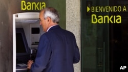 A man uses an ATM cash point machine at a branch of the Bankia bank in Madrid, May 18, 2012.