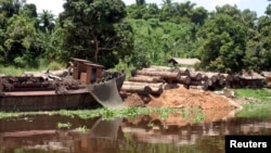 FILE - Logs lie next to a rusting barge on the banks of the Congo river, DRC.