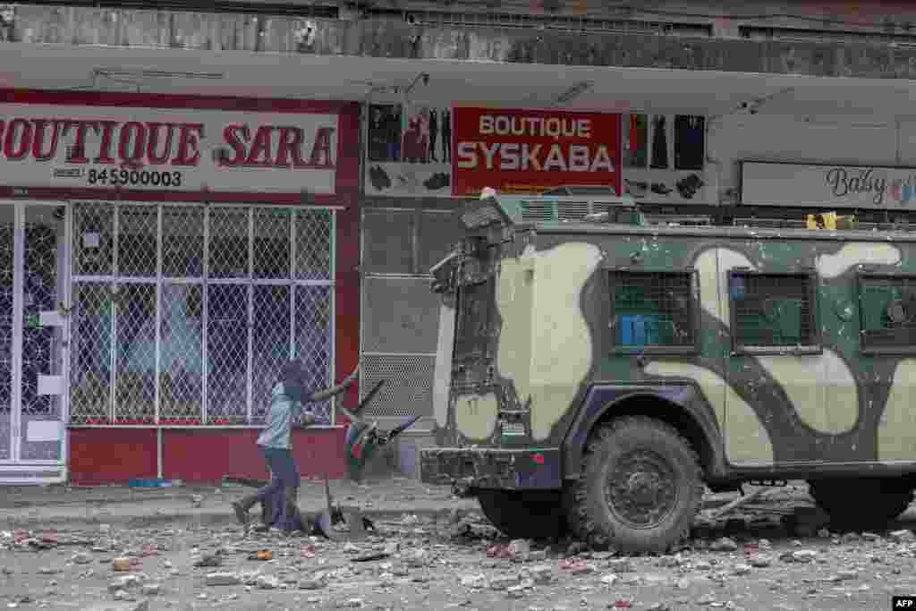 Um manifestante atira uma cadeira de plástico em um veículo blindado enquanto manifestantes entram em confronto com a polícia de choque moçambicana em Maputo, em 27 de novembro de 2024.