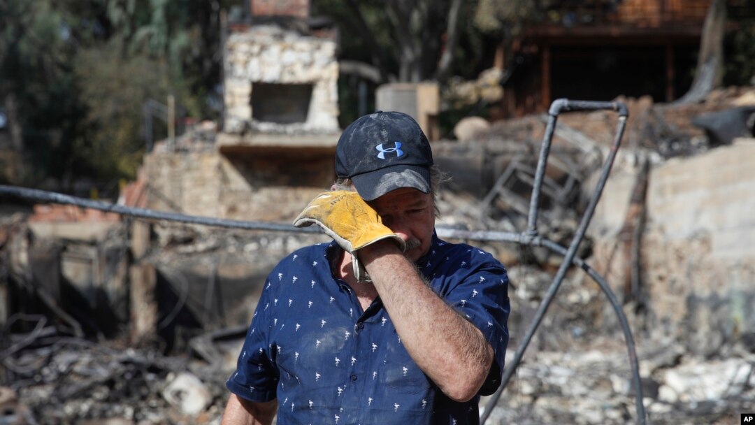 Roger Kelton, 67, wipes his tears while searching through the remains of his mother-in-law's home burned down by the Woolsey Fire, Nov. 13, 2018, in Agoura Hills, Calif. 